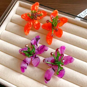 Detailed view of vibrant acrylic flower stud earrings with beaded centers in a tray
