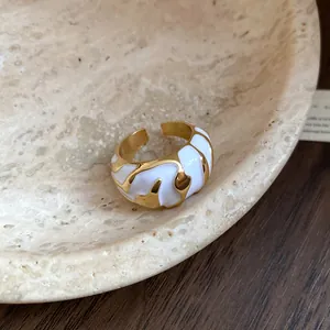 Exquisites Makro-Detail eines goldenen Vintage-Rings mit unregelmäßiger weißer Emaille-Textur.