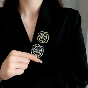 Detailansicht von silbernen und goldenen Rosenbroschen mit Strass auf schwarzem Blazer.