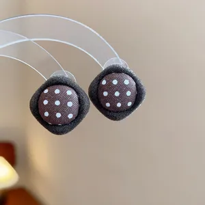 Macro detail of retro polka dot fabric button earrings with dark velvet trim.