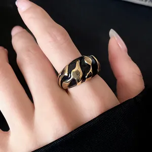 Nahaufnahme eines Vintage-Rings mit goldener Textur und schwarzem Emaille-Muster