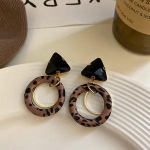 Detalle de pendientes de aro con estampado de leopardo y triángulo geométrico negro
