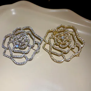 Nahaufnahme von silbernen und goldenen Strass-Rosenbroschen auf einem beigen Tablett