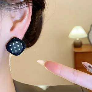 Close-up view of a vintage black polka dot fabric stud earring worn on a model's ear