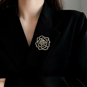 Nahaufnahme einer eleganten, goldfarbenen Strass-Blütenbrosche auf einem schwarzen Blazer.