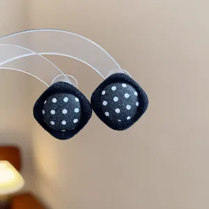 Close-up of retro black and white polka dot fabric stud earrings with elegant velvet border