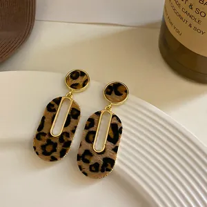 Vista detallada de pendientes geométricos con estampado de leopardo y baño de oro chic
