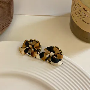 Primer plano de pendientes de lazo con estampado de leopardo y borde dorado en plato