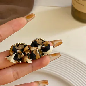 Primer plano de elegantes pendientes de lazo con estampado de leopardo y bordes dorados s925