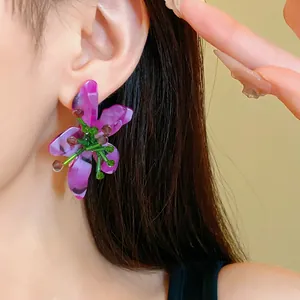 Primo piano di eleganti orecchini a fiore in cristallo viola con perline verdi
