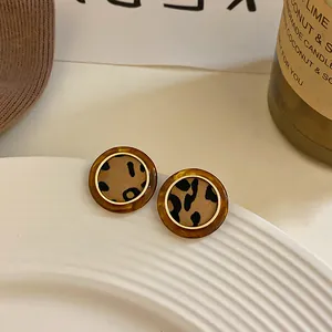 Primer plano detallado de pendientes redondos con estampado de leopardo y borde dorado