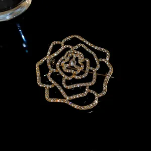 Detailansicht einer eleganten goldenen Rosenbrosche mit vielen funkelnden Kristallen.