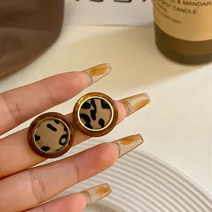 Primer plano de pendientes redondos vintage con estampado de leopardo y resina ámbar.