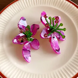 Dettaglio di orecchini a fiore in cristallo fatti a mano su un piatto di ceramica bianca