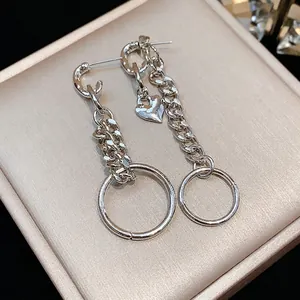 Elegantes pendientes de cadena de corazón plateados con aros grandes en joyero beige