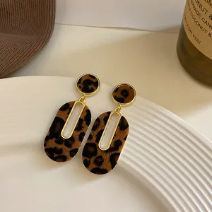 Vista detallada de pendientes ovalados con estampado de leopardo y detalles dorados