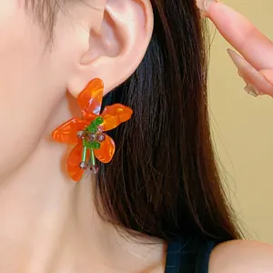 Detailed close-up of a vintage orange crystal flower earring worn on a model's ear