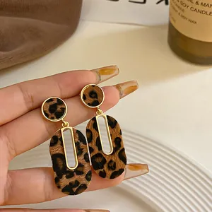 Vista detallada de pendientes ovalados dorados con textura de leopardo muy elegante.