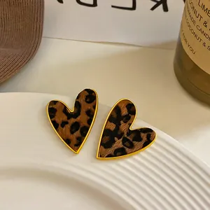 Detalle de pendientes de corazón con estampado de leopardo y borde de metal oro