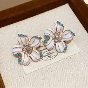 Vintage white enamel flower stud earrings with rhinestones and blue bead accents