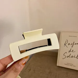 Detailaufnahme einer cremefarbenen geometrischen Haarklammer im Vintage-Stil in der Hand