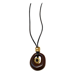 Collier à pendentif ovale en résine marron minimaliste avec accents dorés sur cordon noir.