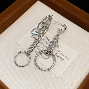 Detalle de pendientes de cadena con corazón plateado en un soporte de joyería vintage.