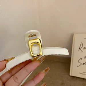 Nahaufnahme einer Vintage cremeweißen geometrischen Haarklammer mit Gold-Metall-Detail