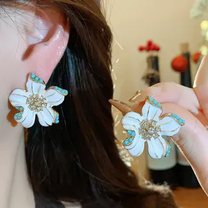 Detailed view of vintage flower earrings with white enamel and rhinestone accents