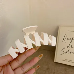 Detail einer cremefarbenen geometrischen Haarspange für elegante Frisuren mit mattem Finish.