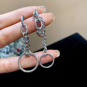 Detalle de los pendientes de cadena de metal plateado con dije de corazón y aros