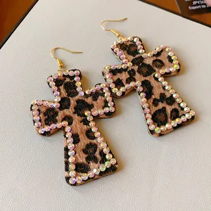 Primer plano de pendientes de cruz con estampado de leopardo y borde de pedrería