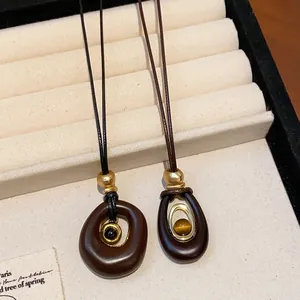 Détail macro de pendentifs minimalistes en résine œil de tigre sur cordons longs