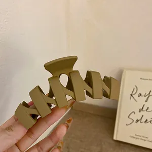 Nahaufnahme einer großen, matt-kaffeebraunen geometrischen Haarklammer, die in der Hand gehalten wird