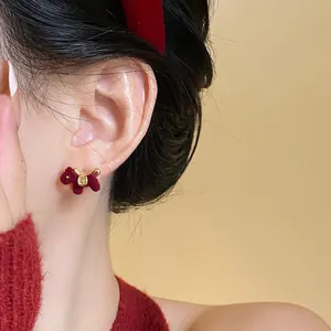Primer plano de un lindo pendiente de caballo flocado rojo para mujer en la oreja