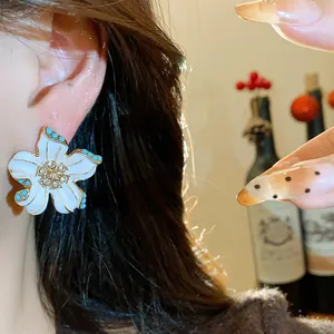 Close-up of vintage flower stud earring with enamel petals and rhinestone center