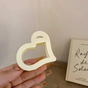 Detailansicht einer minimalistischen, cremefarbenen, hohlen Haarklammer in Herzform