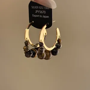 Dettaglio di orecchini a cerchio vintage in occhio di tigre con perni in argento 925