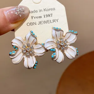 Vintage enamel flower stud earrings with rhinestones and blue bead accents on silver pins