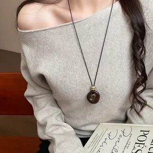 Gros plan d'un pendentif en résine œil de tigre minimaliste sur un long collier pull