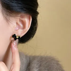 Detalle de elegantes pendientes de poni flocado negro con detalles dorados en la oreja