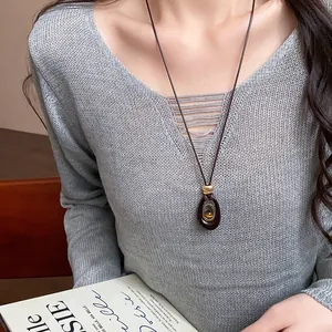 Vue détaillée du collier minimaliste en résine ovale avec œil de tigre sur un long cordon réglable