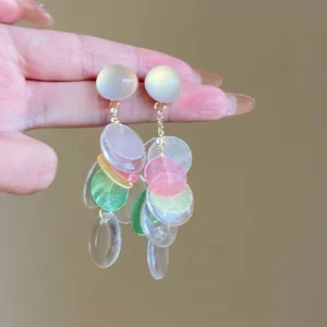 Dettaglio di orecchini a nappa in resina colorata con perni in argento dal design dolce.