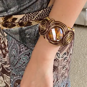 Detail of a luxurious twisted wire cuff bracelet featuring a large amber-colored crystal stone