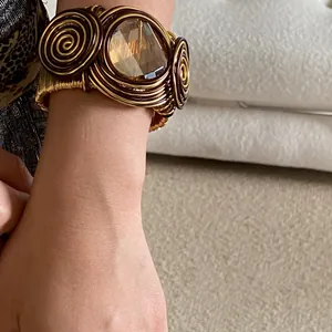 Detailed shot of bohemian woven gold wire cuff bracelet with amber glass stone