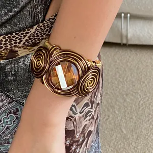 Close-up detail of a handmade twisted wire cuff bracelet featuring a large amber gemstone.