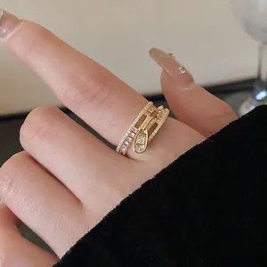 Close-up of a gold-colored open ring featuring a creative zipper design set with zircons.