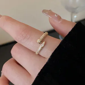 Close-up of an elegant gold-plated zircon snake-shaped adjustable open ring on a finger.