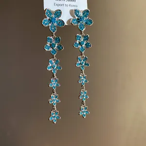Close-up of elegant floral dangle earrings with sparkling blue zircons
