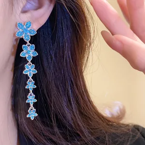Elegant silver needle drop earrings with blue zircon flower tassels worn by a model